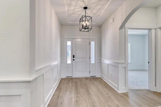 4028 Bucolic Loop, Myrtle Beach, SC 29588 - entryway with a decorative wall, light wood-type flooring, arched walkways, a chandelier, and a wainscoted wall