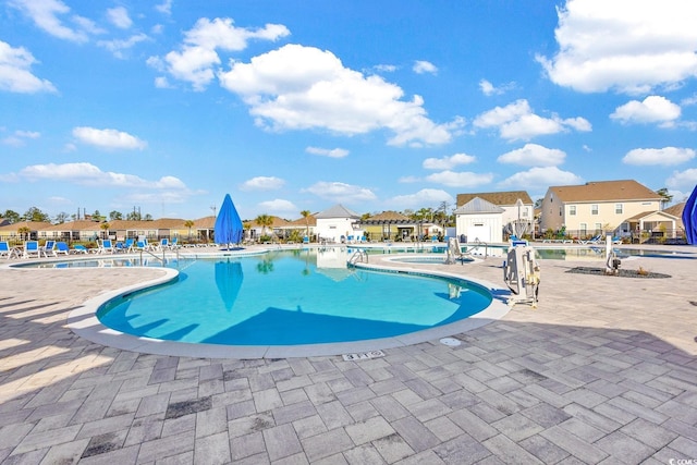 community pool featuring a patio area, a residential view, and fence