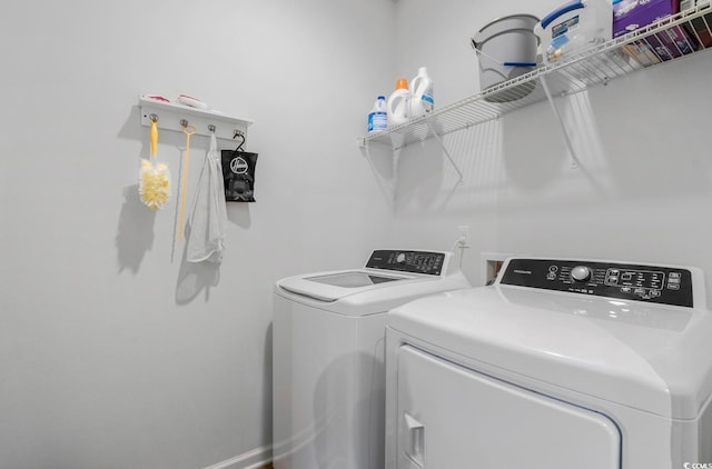 clothes washing area with baseboards, laundry area, and washer and clothes dryer