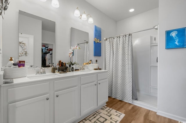 bathroom featuring double vanity, a sink, curtained shower, and wood finished floors