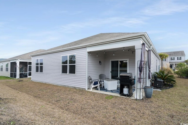 rear view of property with a patio, a lawn, and a sunroom