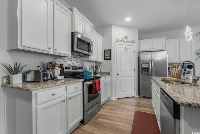 kitchen with a sink, light wood-type flooring, appliances with stainless steel finishes, and white cabinets