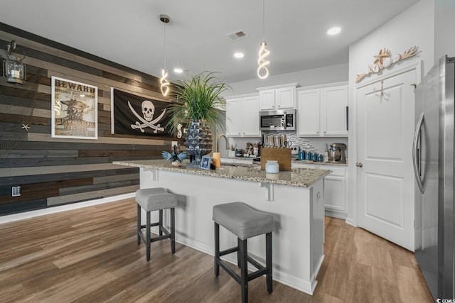 kitchen with white cabinetry, light stone countertops, visible vents, appliances with stainless steel finishes, and wood finished floors