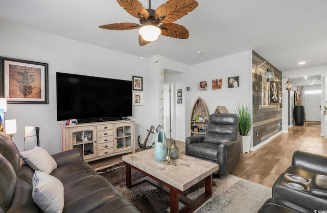 living room with wood finished floors, baseboards, and ceiling fan