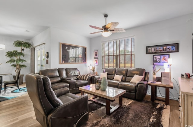 living room with ceiling fan, baseboards, and wood finished floors