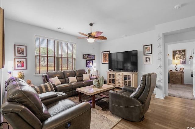 living room featuring a ceiling fan, wood finished floors, visible vents, and baseboards