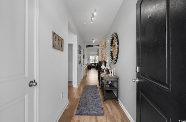 corridor featuring light wood-type flooring and baseboards