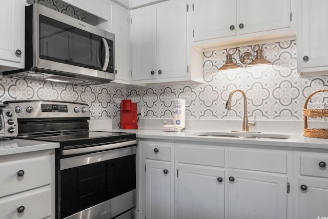 kitchen featuring light countertops, appliances with stainless steel finishes, white cabinetry, and a sink
