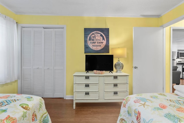 bedroom with baseboards, a closet, ornamental molding, and dark wood finished floors