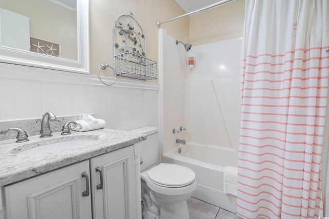 full bath featuring a wainscoted wall, tile patterned floors, toilet, vanity, and shower / tub combo with curtain