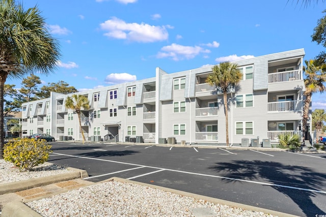 view of building exterior featuring uncovered parking and central AC