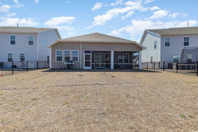 back of property featuring a lawn, a sunroom, and a fenced backyard