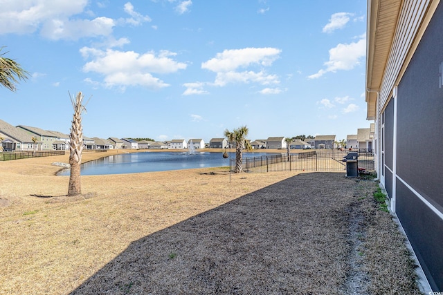 view of yard featuring fence, a water view, and a residential view