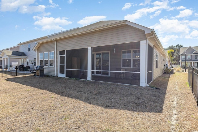 rear view of property featuring a sunroom and a fenced backyard