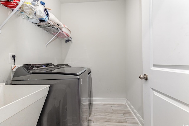 clothes washing area featuring a sink, separate washer and dryer, laundry area, baseboards, and marble finish floor