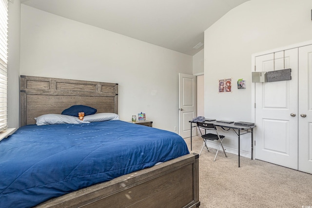 bedroom with lofted ceiling, light carpet, and a closet