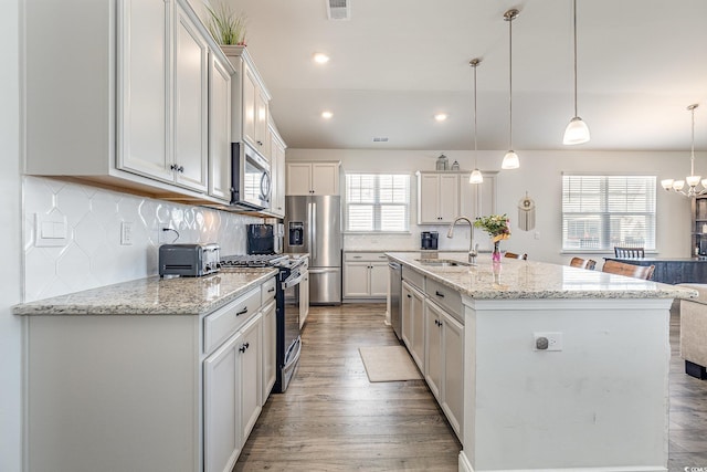 kitchen featuring light wood-style flooring, visible vents, a sink, backsplash, and stainless steel appliances