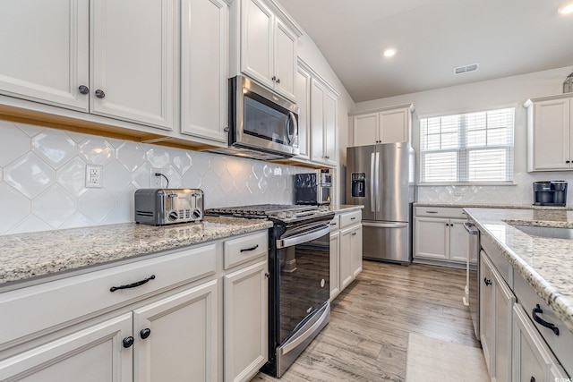 kitchen with light wood-style flooring, a sink, white cabinets, visible vents, and appliances with stainless steel finishes