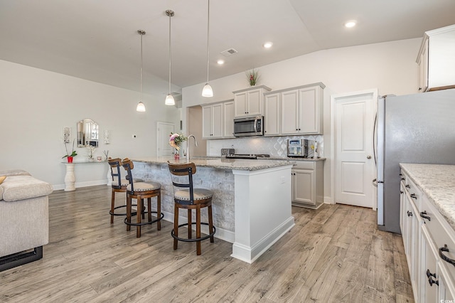 10141 Hamilton Branch Loop, Myrtle Beach, SC 29579 - kitchen with lofted ceiling, stainless steel appliances, light wood-type flooring, a center island with sink, and a kitchen bar