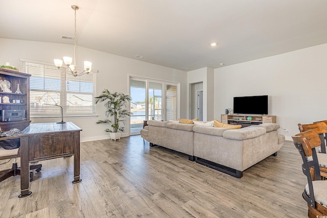living area with baseboards, a notable chandelier, light wood finished floors, and visible vents