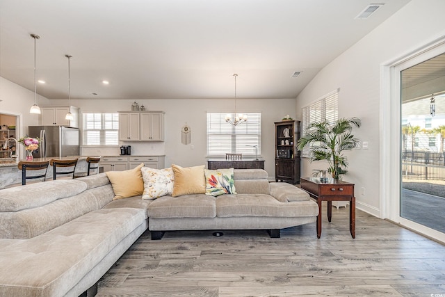 living area featuring recessed lighting, visible vents, light wood-style flooring, and a notable chandelier