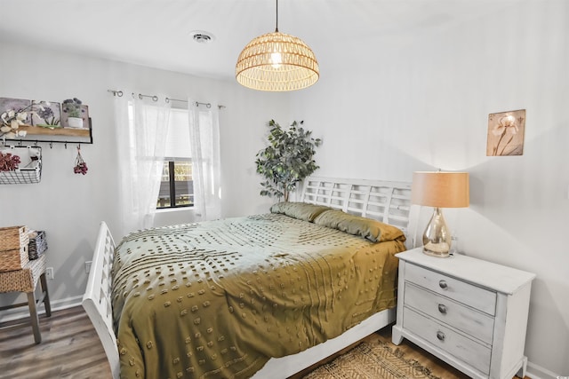 bedroom with visible vents, baseboards, and wood finished floors