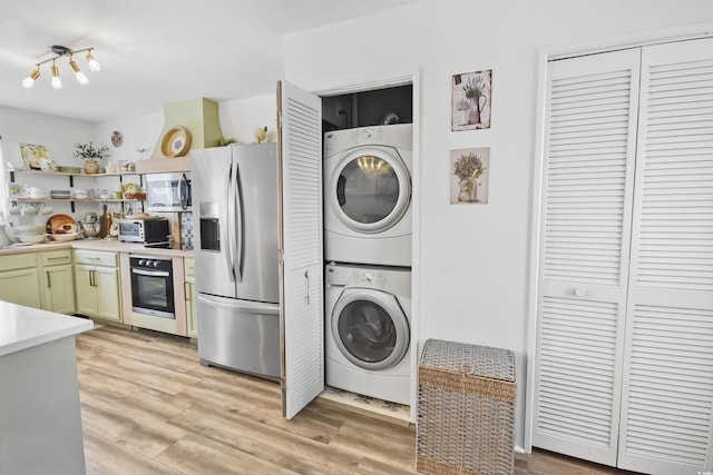 kitchen featuring open shelves, stainless steel appliances, light countertops, stacked washer and clothes dryer, and light wood-type flooring