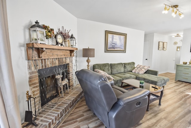 living room with a brick fireplace, wood finished floors, and baseboards