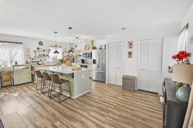 kitchen featuring a breakfast bar, light countertops, light wood-style floors, and appliances with stainless steel finishes