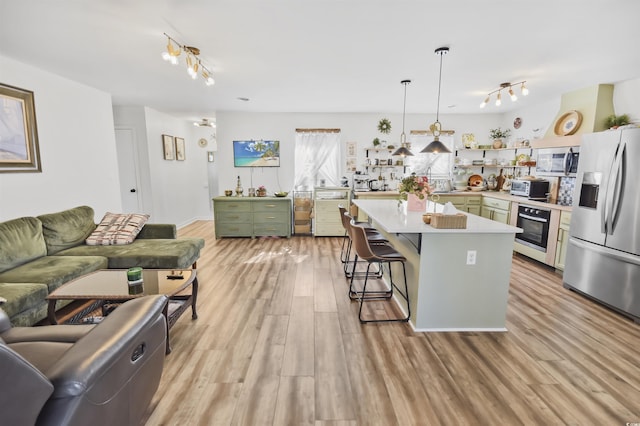 kitchen featuring light countertops, a kitchen breakfast bar, light wood-style floors, stainless steel appliances, and open shelves