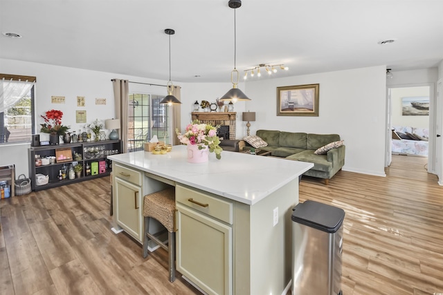 kitchen with a center island, hanging light fixtures, light countertops, and light wood finished floors