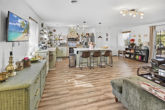 kitchen featuring stainless steel appliances, light wood-style floors, a breakfast bar area, light countertops, and hanging light fixtures