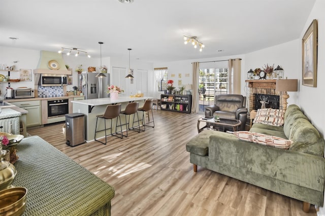 living area with a toaster, a fireplace, and light wood-type flooring