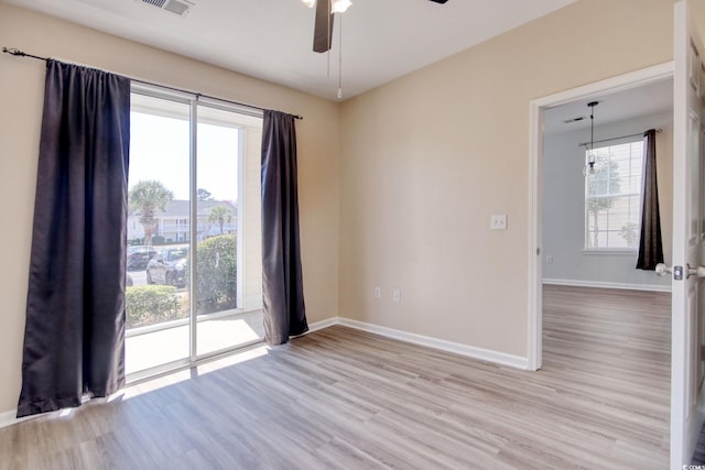 empty room with visible vents, baseboards, light wood finished floors, and ceiling fan