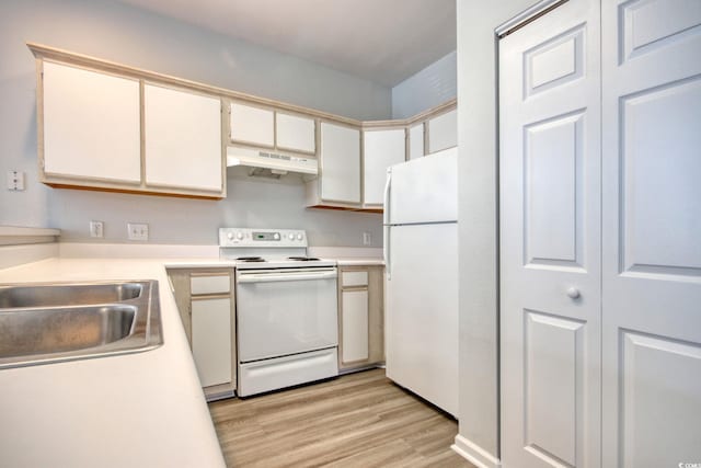kitchen with under cabinet range hood, light countertops, light wood-style floors, white appliances, and a sink