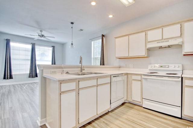 kitchen featuring light wood-style flooring, under cabinet range hood, a sink, white appliances, and a peninsula