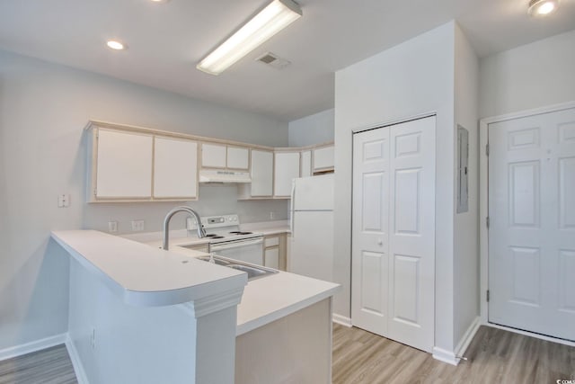 kitchen featuring under cabinet range hood, white appliances, light wood-style floors, a peninsula, and light countertops