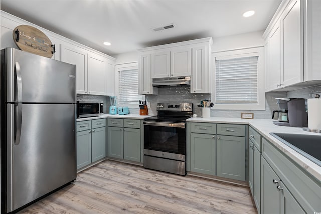 kitchen featuring light wood finished floors, visible vents, under cabinet range hood, light countertops, and stainless steel appliances