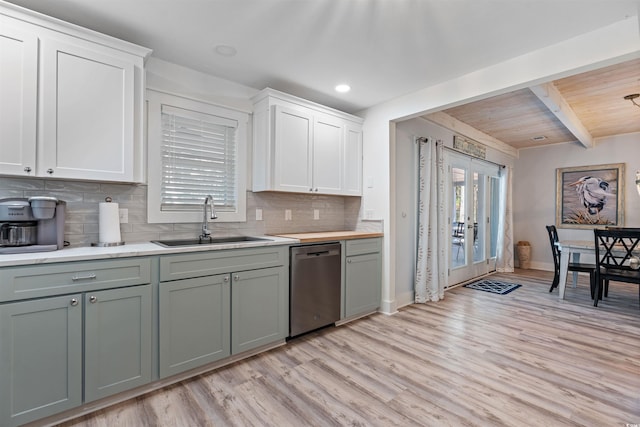 kitchen featuring light wood finished floors, a healthy amount of sunlight, dishwasher, light countertops, and a sink