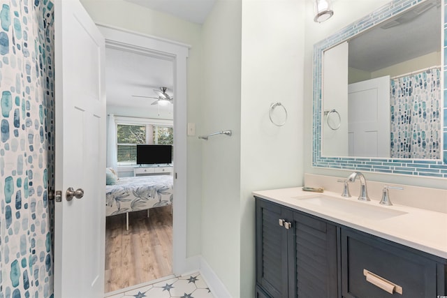 ensuite bathroom with ceiling fan, baseboards, ensuite bath, and vanity