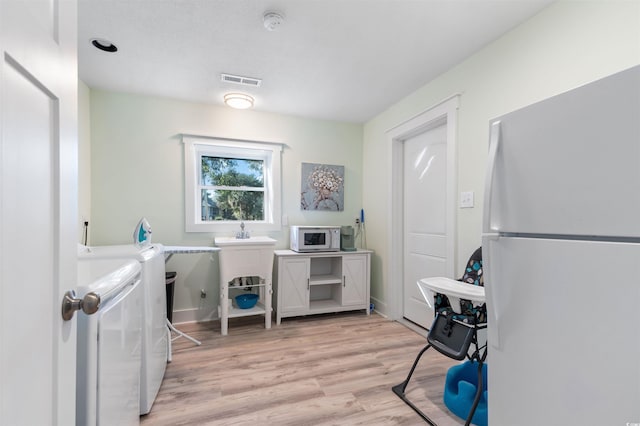 laundry area featuring visible vents, light wood-style floors, and washing machine and dryer