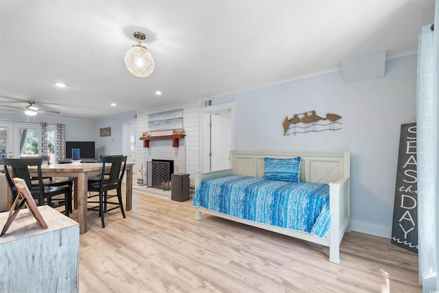 bedroom featuring visible vents, ornamental molding, a brick fireplace, and wood finished floors