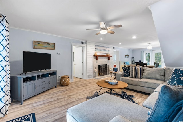 living area with visible vents, crown molding, a fireplace, and light wood finished floors