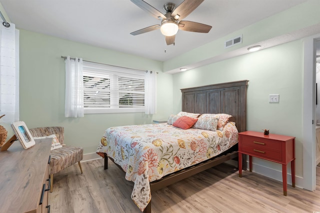 bedroom featuring ceiling fan, visible vents, baseboards, and light wood-style flooring