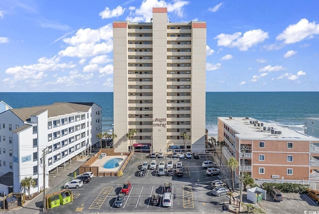 view of building exterior featuring uncovered parking and a water view