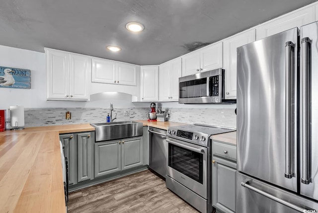 kitchen featuring a sink, butcher block counters, gray cabinetry, and stainless steel appliances