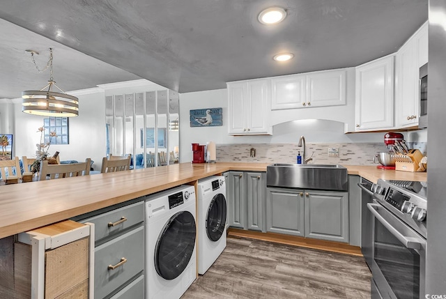 kitchen with light wood finished floors, gray cabinets, a sink, stainless steel range, and butcher block counters