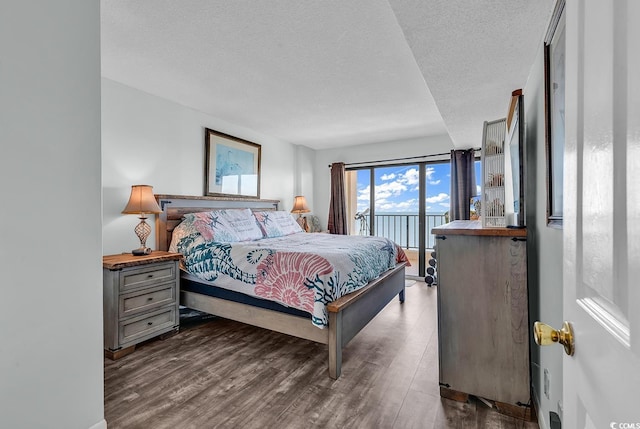 bedroom with dark wood-style floors, a textured ceiling, and access to outside