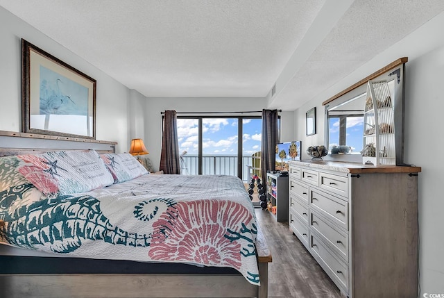 bedroom featuring access to exterior, dark wood-style floors, visible vents, and a textured ceiling