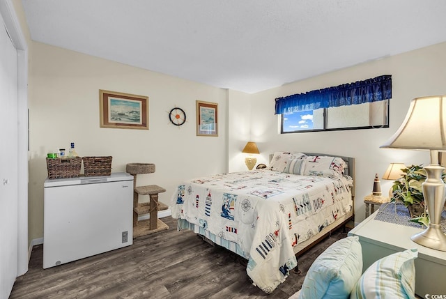 bedroom with dark wood-style floors, white refrigerator, and baseboards